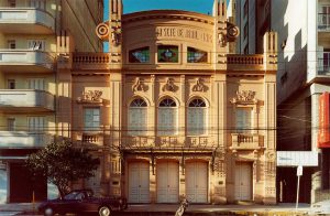 Imagem da fachada do teatro Sete de abril. Ele é amarelo claro, tem um vitral, janelas e portas grandes.